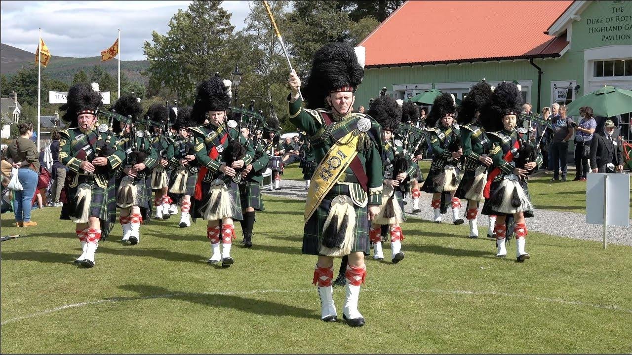 Drum major leads Huntly Pipe Band playing Cullen Bay during 2023 Braemar Gathering Highland Games