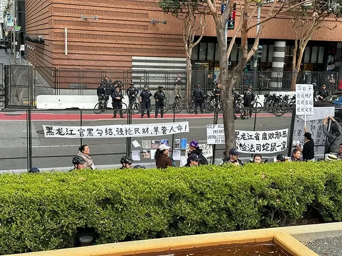 访民打出抗议横幅，道路对面是骑车前来的警察